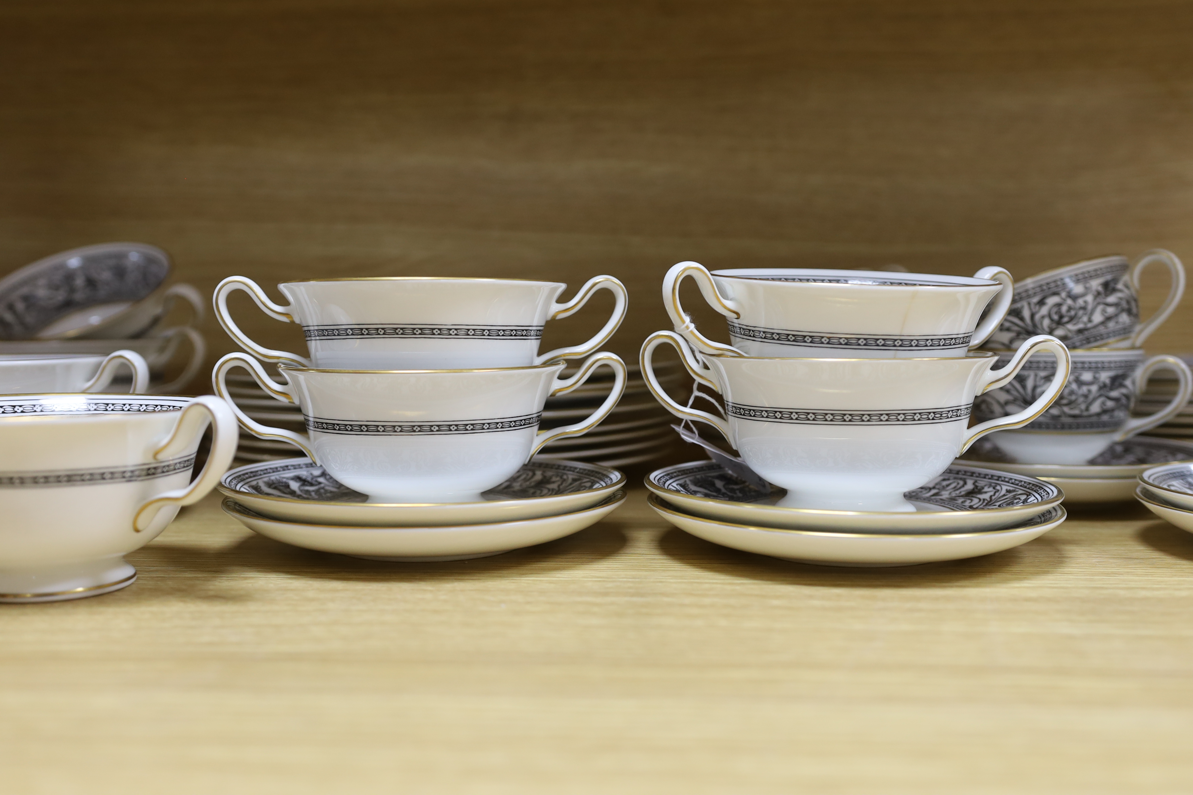 A Wedgwood Florentine part dinner set including twin handled cups, oval platter and dinner plates, largest 34cm wide